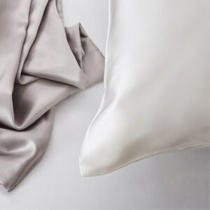 KT Milano silk pillowcase with a soft blush pink silk scarf draped over it, accompanied by matching silk hair scrunchies, showcasing a luxurious sleep and hair care accessory set.