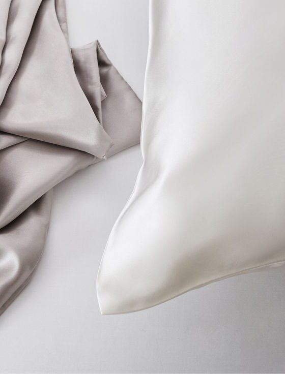 KT Milano silk pillowcase with a soft blush pink silk scarf draped over it, accompanied by matching silk hair scrunchies, showcasing a luxurious sleep and hair care accessory set.